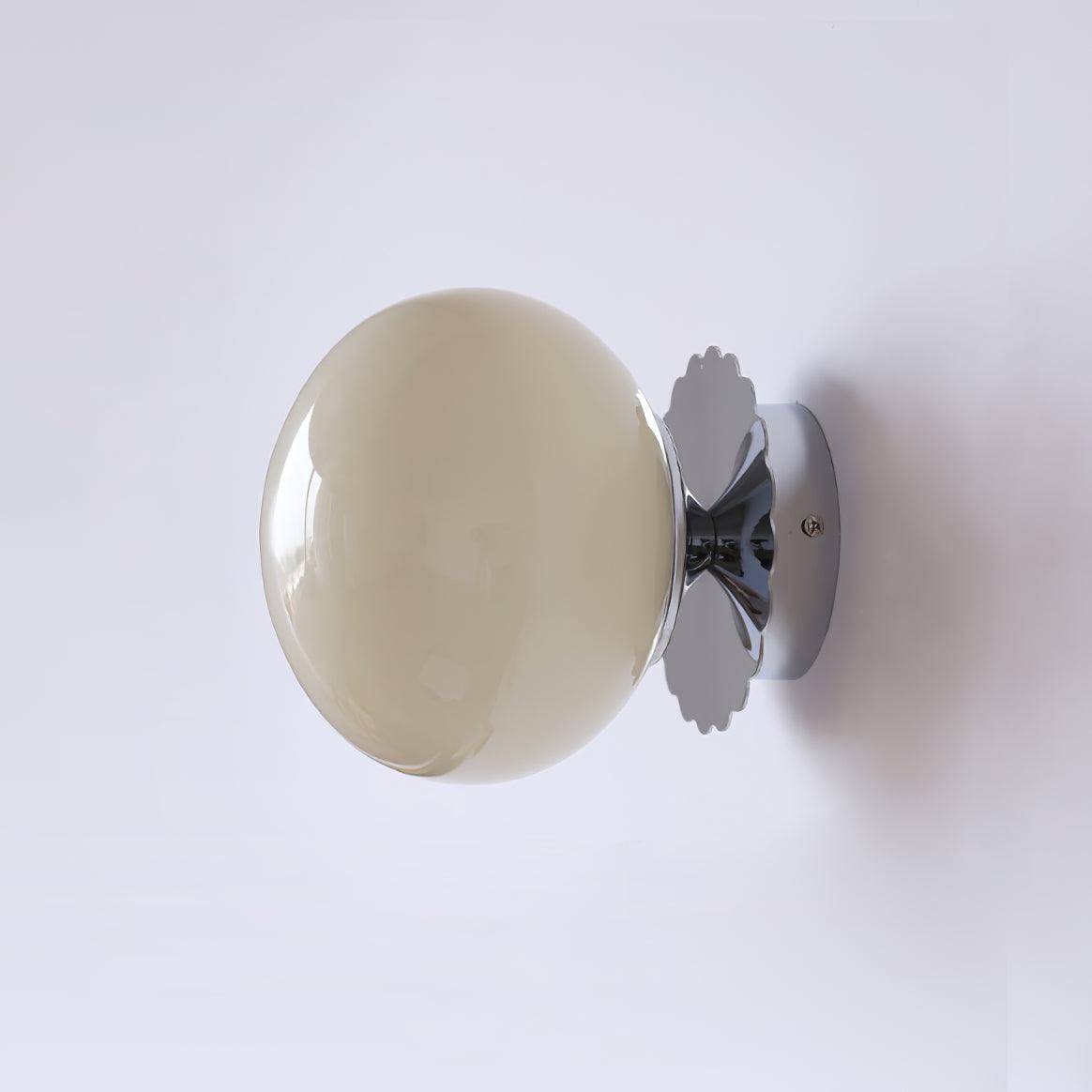Wall sconce with tinted glass shade mounted beside a mirror