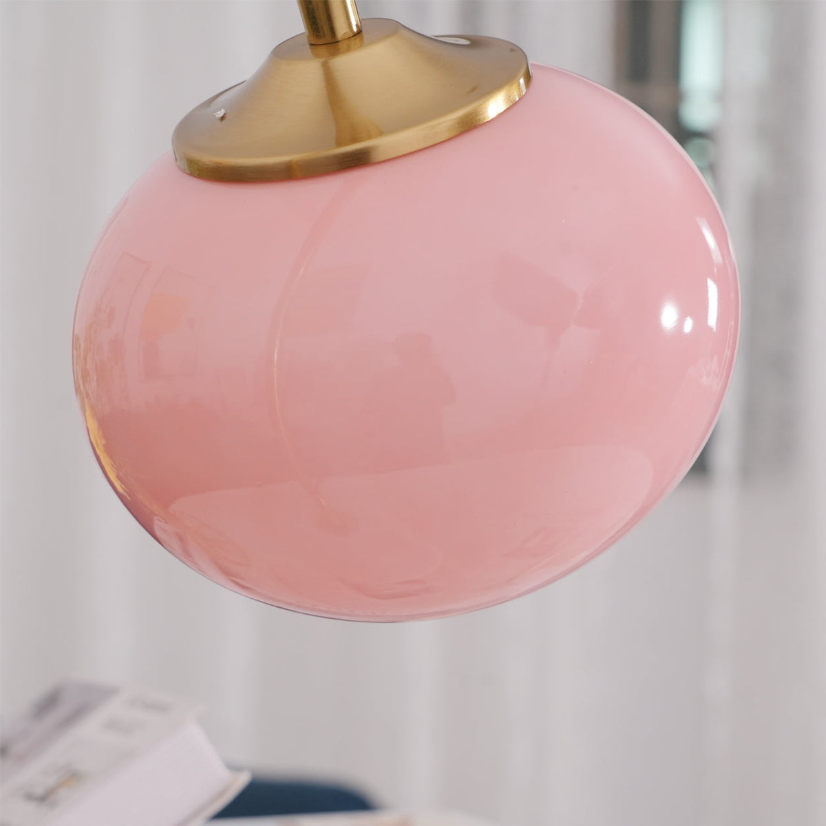 Extreme close-up of the Clérachic table lamp's glossy pink glass shade and gold cap, showing the smooth rounded curve of the glass.