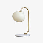 Clérachic pastel glass table lamp with an off-white globe shade on a brass arm and oval marble base, shown unlit on a plain white backdrop.