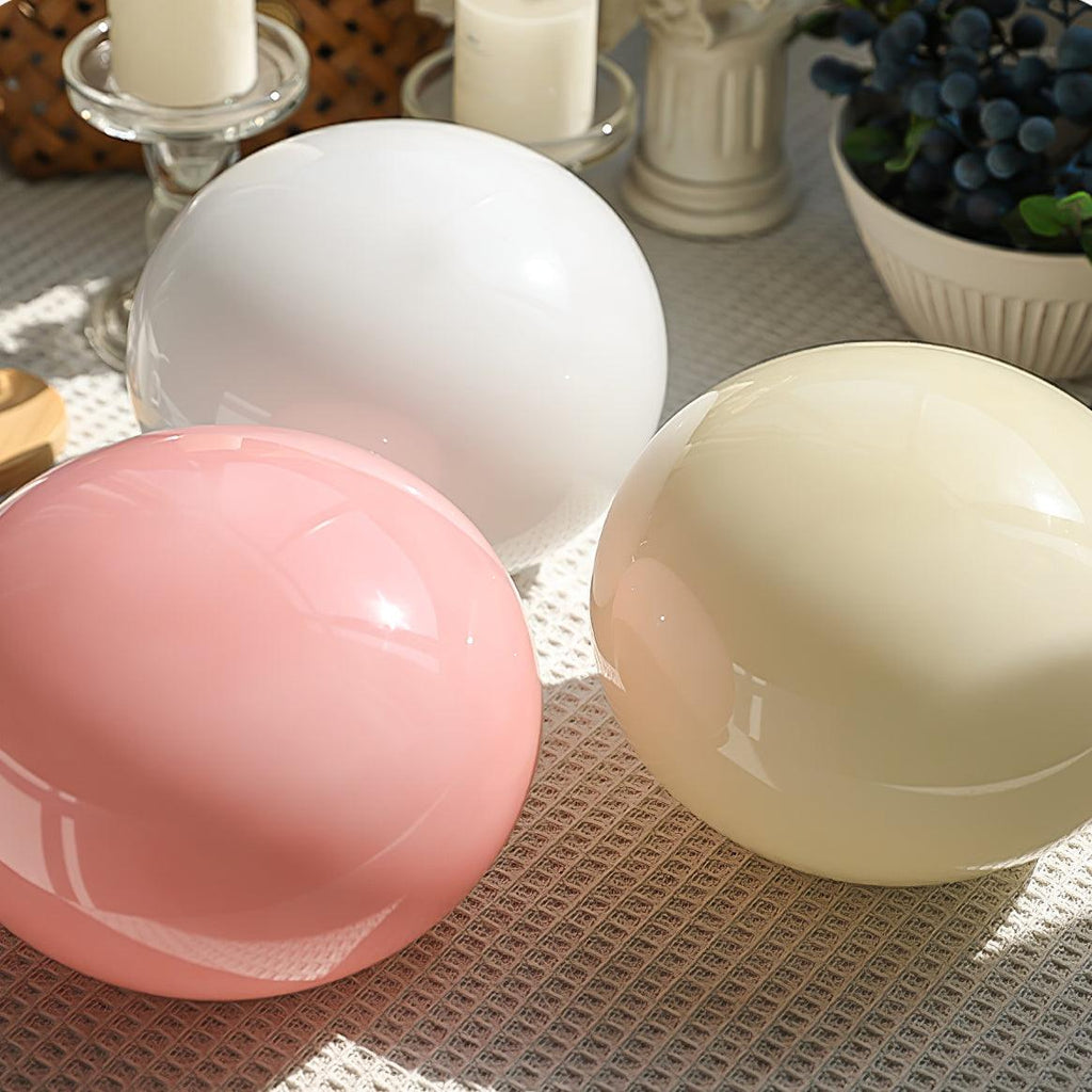 Three Clérachic table lamp glass shades in white, pink and cream sit together on a woven mat, showing the colour options side by side.