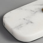 Close-up of the Clérachic table lamp's rectangular white marble base, its grey veining visible against a plain grey background.