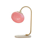 Clérachic pastel glass table lamp with a pink glass shade on a gold arm and marble base, photographed unlit against plain white.