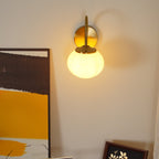Mounted beside abstract art in mustard and brown tones, this Clérachic wall light in copper and beige glass glows warm.