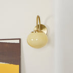 Abstract art in mustard and brown tones sits beside this Clérachic wall light in copper and beige glass, unlit.