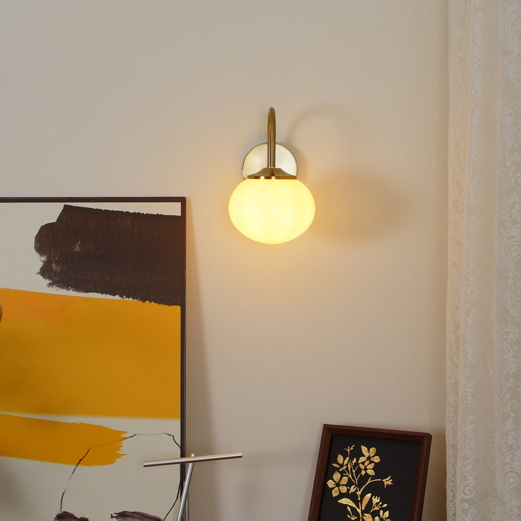 Mounted beside abstract art, this Clérachic wall light in copper and white glass glows warm against sheer curtains.
