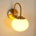 Warm light from this Clérachic wall light in copper and beige glass falls on a soft peach-toned wall.