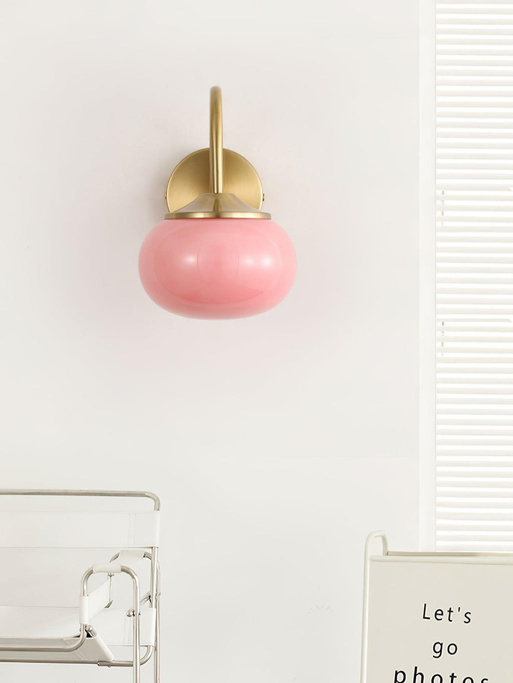 A glass shelf unit sits below this Clérachic wall light in copper and pink glass, mounted on a plain white wall.