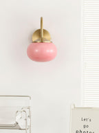 A glass shelf unit sits below this Clérachic wall light in copper and pink glass, mounted on a plain white wall.