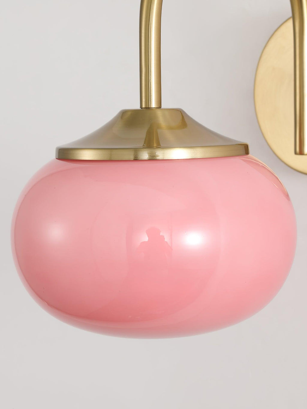 Close view of the pink glass shade on this Clérachic wall light, showing its rounded, bulbous form.