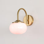 A pink glass shade catches the light on this Clérachic wall light in copper, unlit, on a plain white wall.
