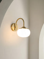 Mounted in a curved alcove, this Clérachic wall light in copper and white glass sits unlit against a soft grey wall.