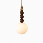 Wood-bead pendant light shown lit against a pale wall