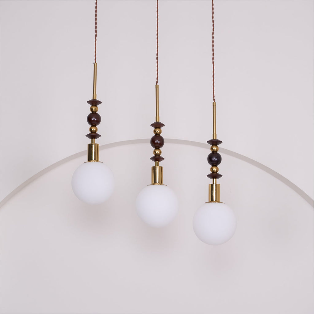 Ash wood pendant light shown lit above a styled space