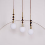 Ash wood pendant light shown lit above a styled space