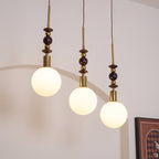 Wood-bead pendant light with white glass shade, lit warm