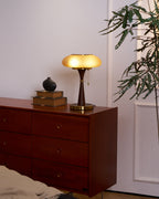 Matsutake table lamp lit warm beside a stack of books