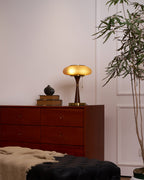 Table lamp with textured glass cap casting a warm amber glow