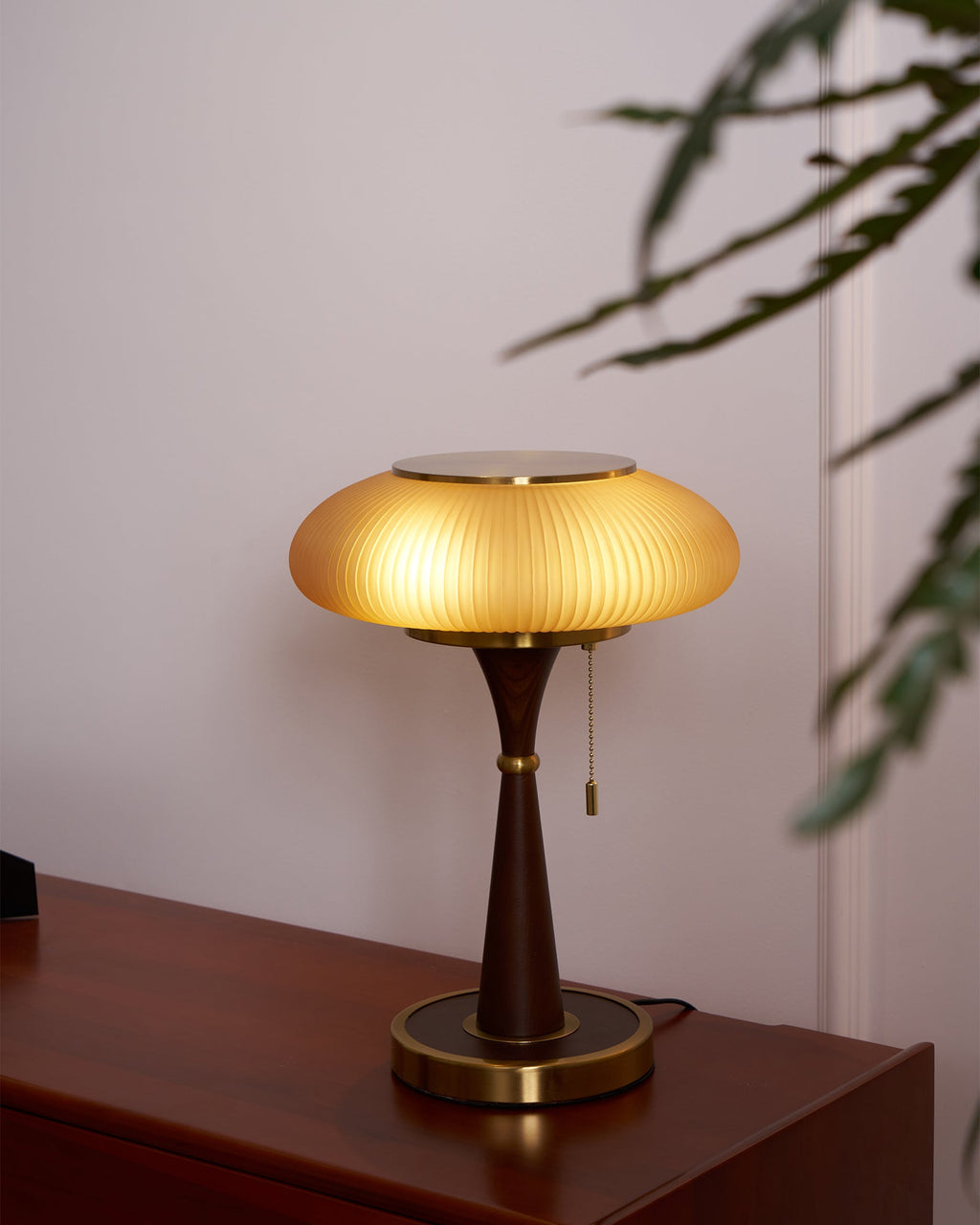 Matsutake table lamp with amber glass shade beside a chair