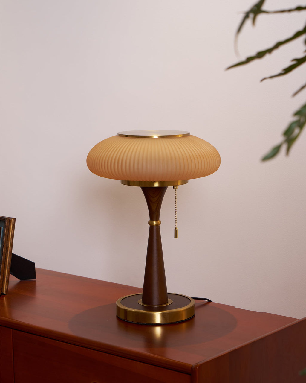 Curved-base table lamp with textured glass cap, lit softly