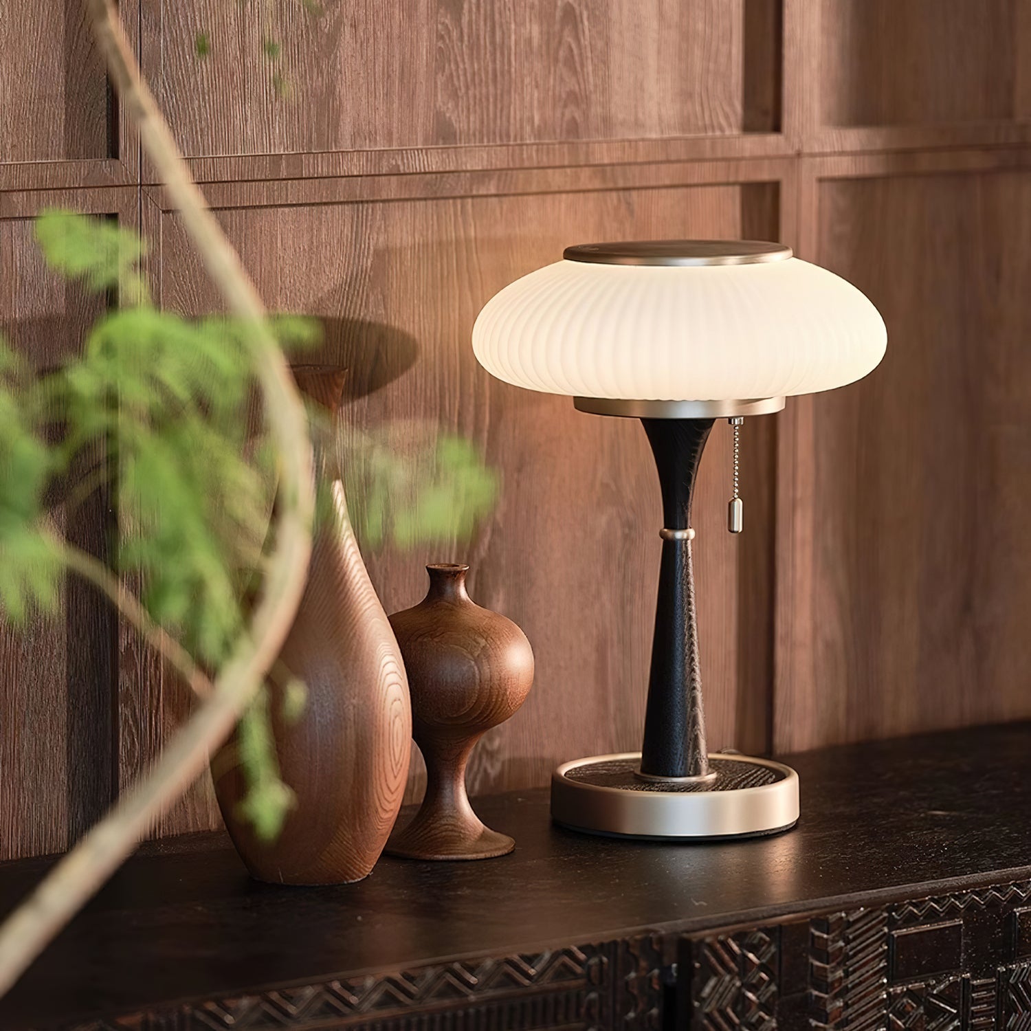 Glass-cap table lamp with curved base on a bedside table
