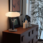 Table lamp with glass cap shade glowing warm in a bedroom