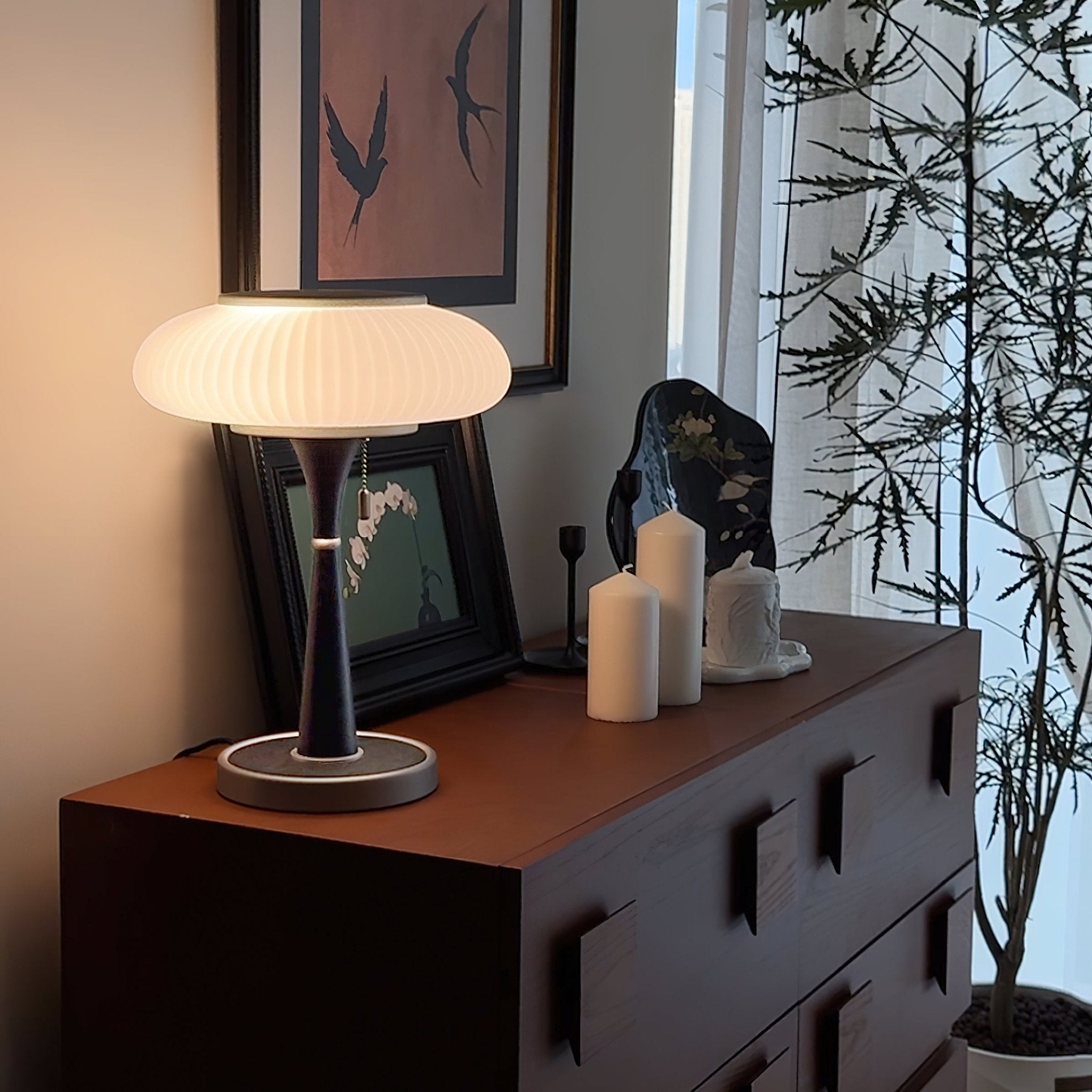 Table lamp with glass cap shade glowing warm in a bedroom