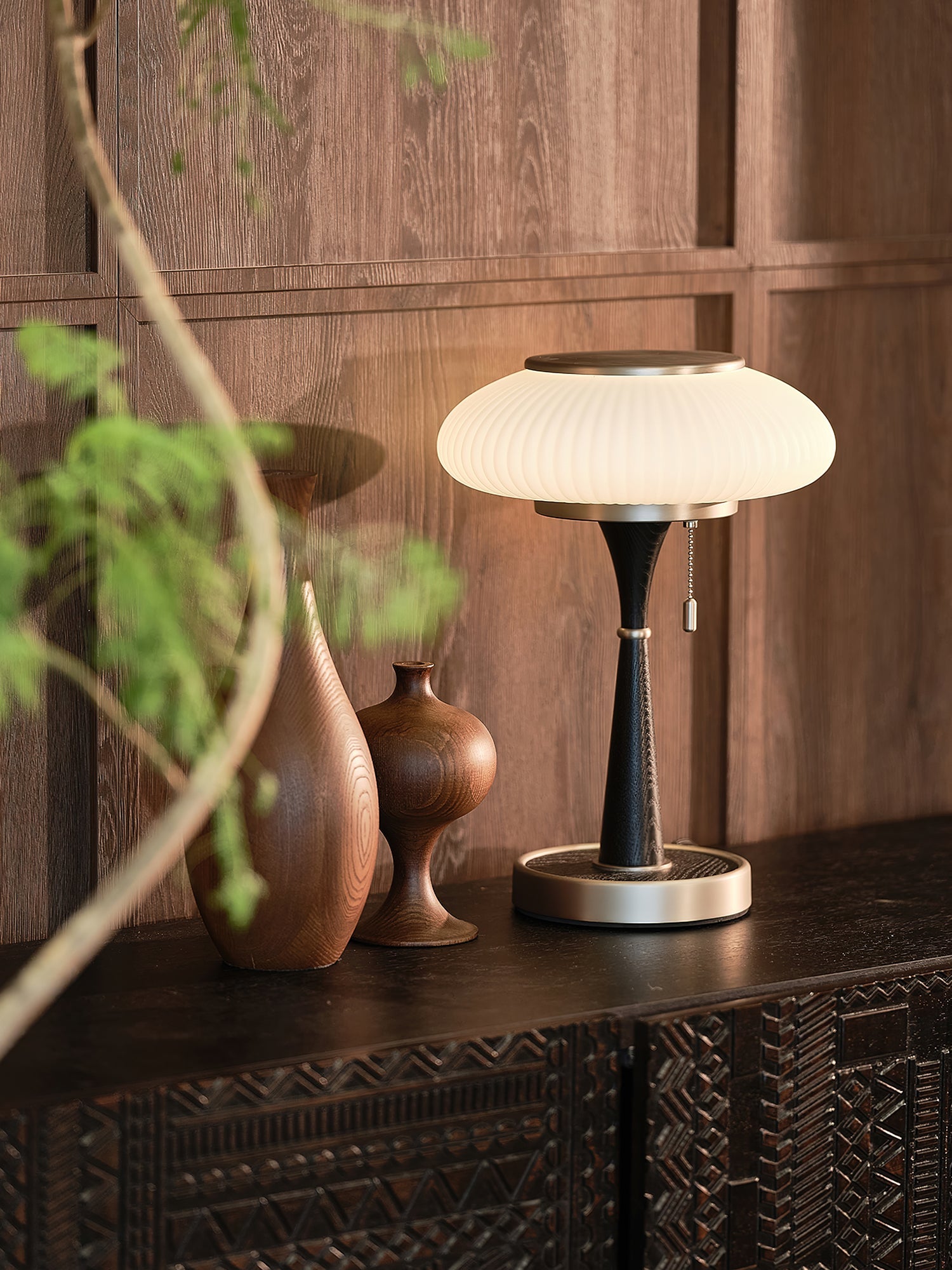 Mushroom glass table lamp glowing amber beside a bed