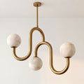 Lit against a plain wall with no other furniture in view, this Clérachic chandelier shows off its brass finish and alabaster globes.