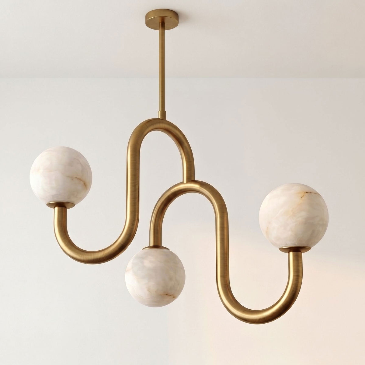 Lit against a plain wall with no other furniture in view, this Clérachic chandelier shows off its brass finish and alabaster globes.