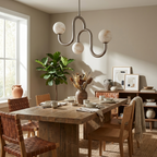 Hanging over a dining table with woven-leather chairs and a potted fig, the nickel finish of this Clérachic chandelier reflects the daylight.