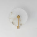 Studio shot of this Clérachic wall sconce in brushed brass, the arm mounted straight down the disc's centre.