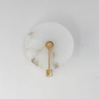Studio shot of this Clérachic wall sconce in brushed brass, the arm mounted straight down the disc's centre.