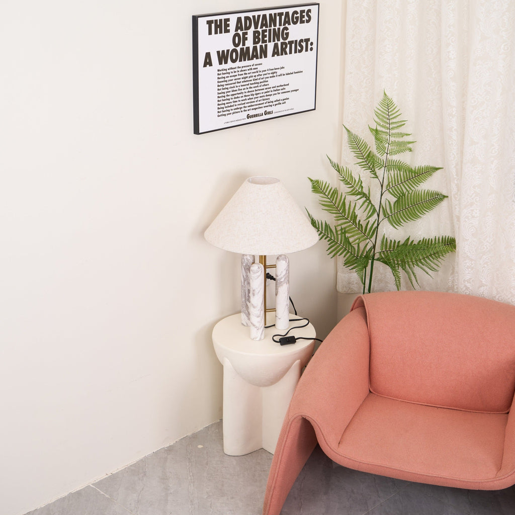 Clérachic table lamp with its cord and switch visible, a framed print above and the coral armchair partly in shot.