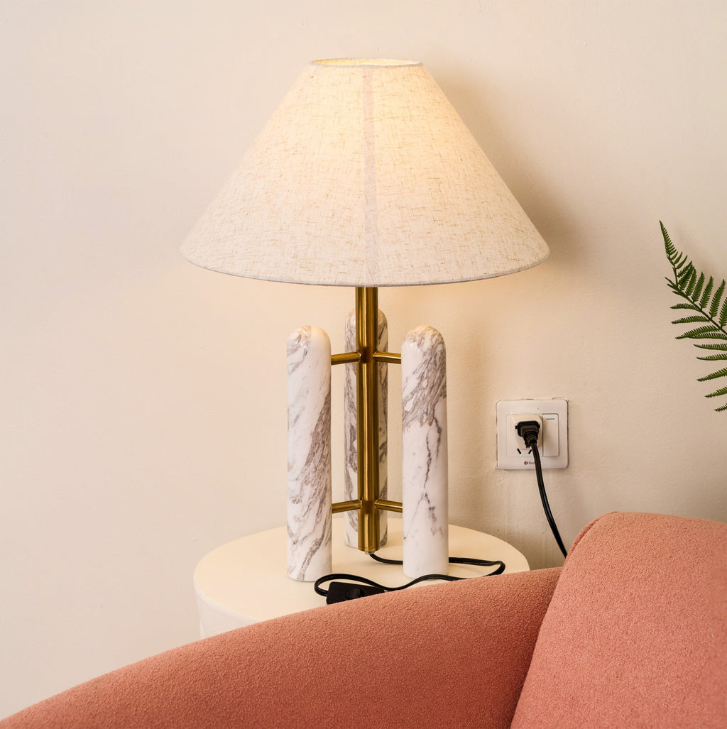 Clérachic table lamp lit and plugged into a wall socket, a fern to one side and the coral armchair's edge in the corner.