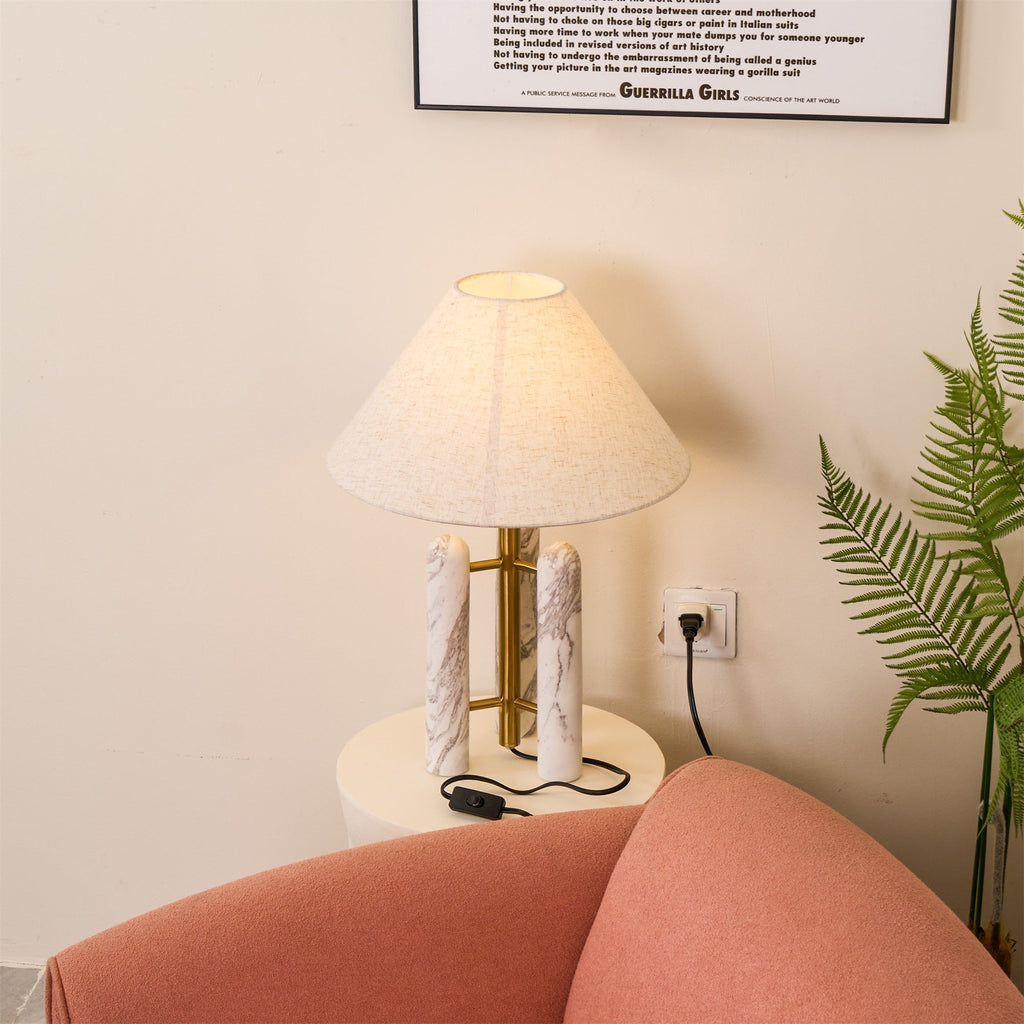 Clérachic table lamp lit in the corner, a wall socket above and the tiled floor visible beneath the fern.