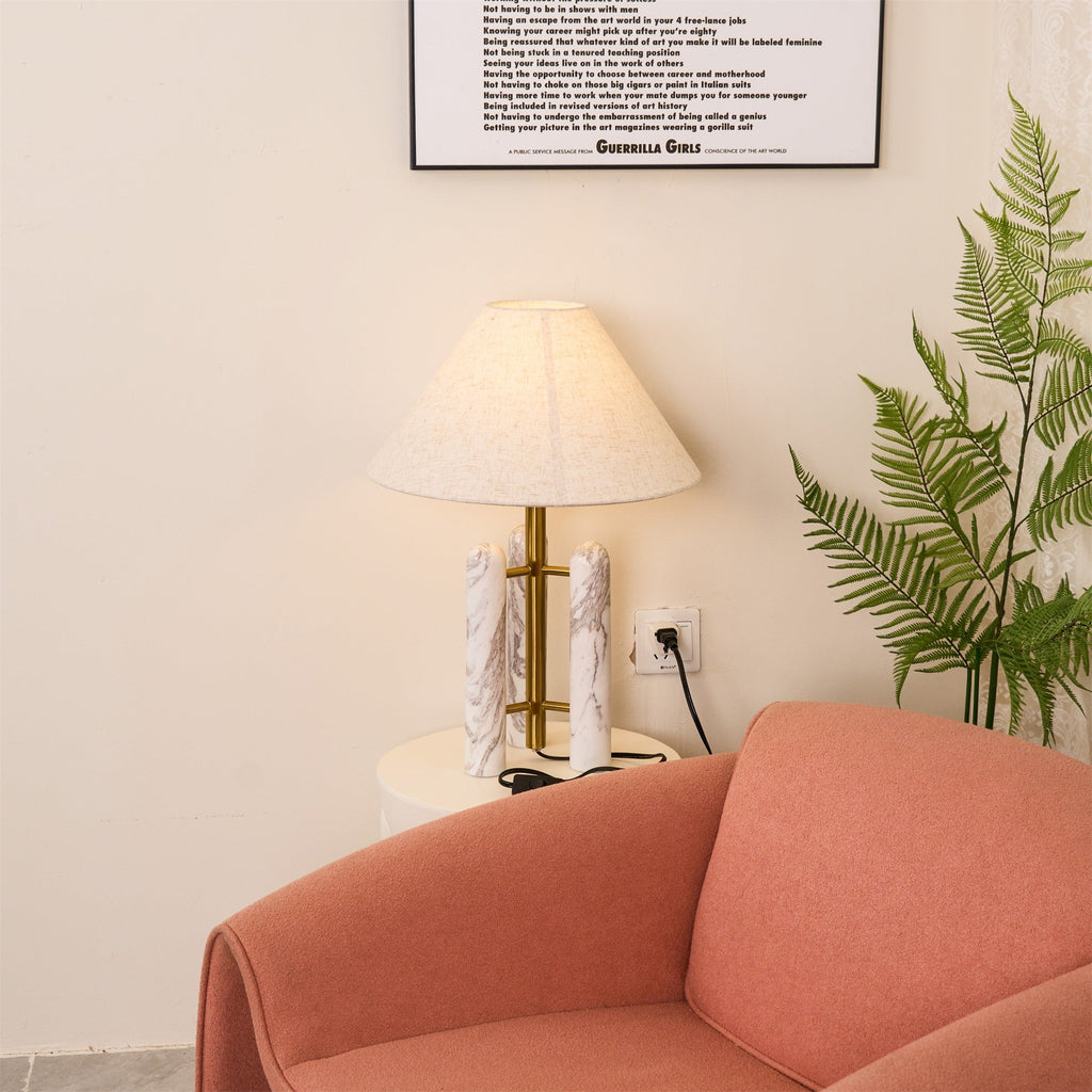 Clérachic table lamp glowing more brightly in the corner, the fern larger in frame and the armchair close beneath it.