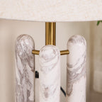 Macro shot of the Clérachic lamp's three marble columns meeting the brass crossbar, veining clearly visible.