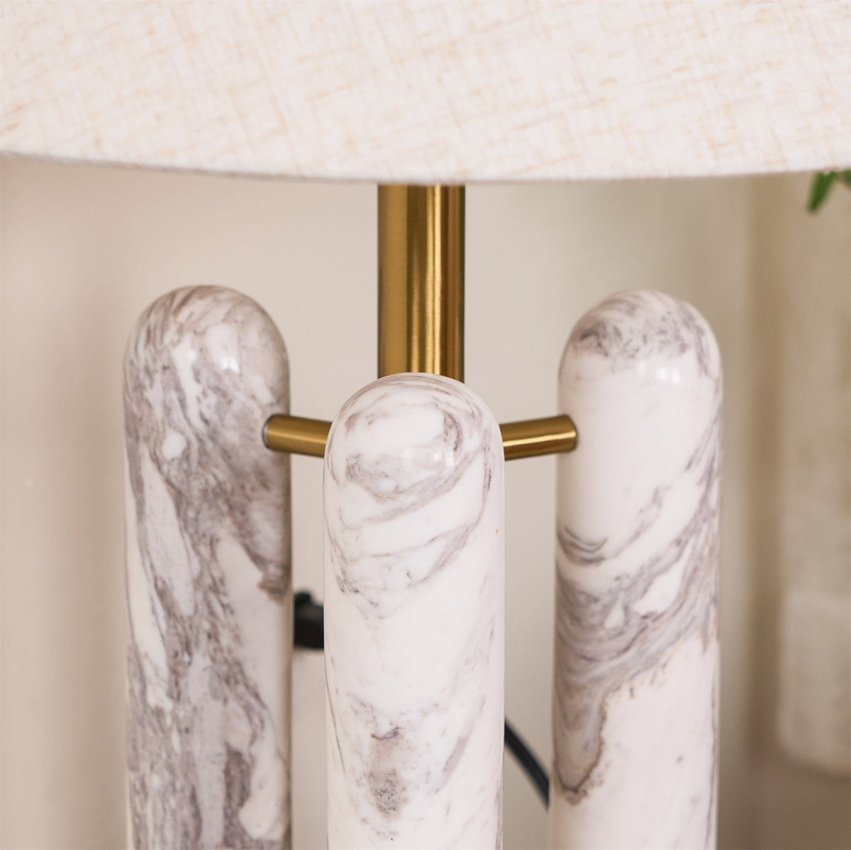Macro shot of the Clérachic lamp's three marble columns meeting the brass crossbar, veining clearly visible.
