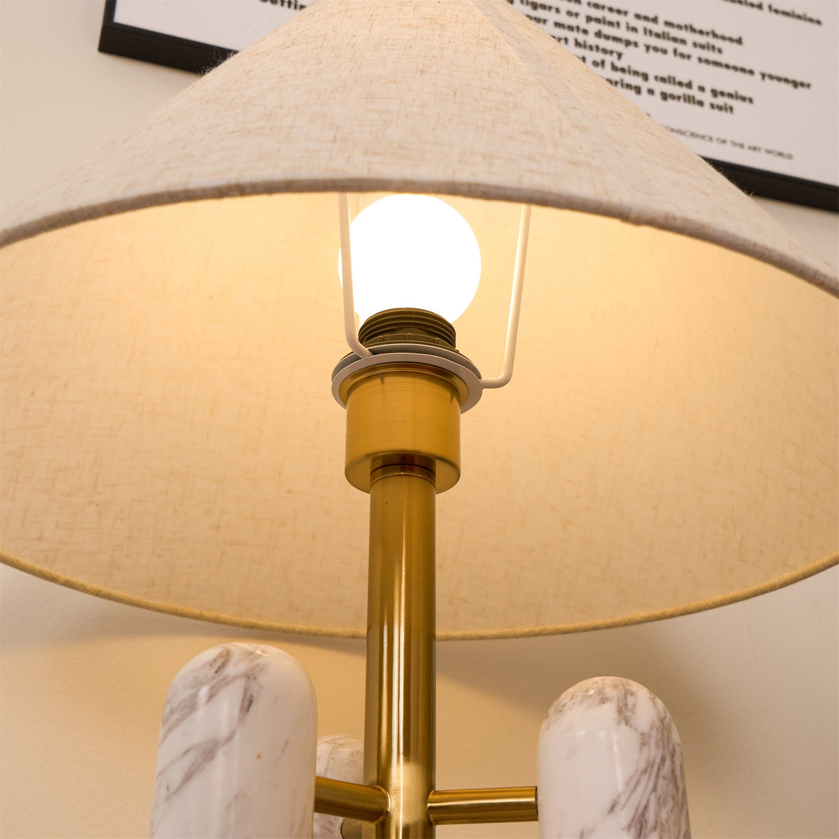 Close-up of the lit bulb inside the Clérachic lamp's shade, the brass socket bright against the fabric.