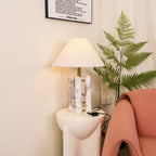 Clérachic table lamp in the same corner, angled to show more of the coral armchair's seat beside the fern.