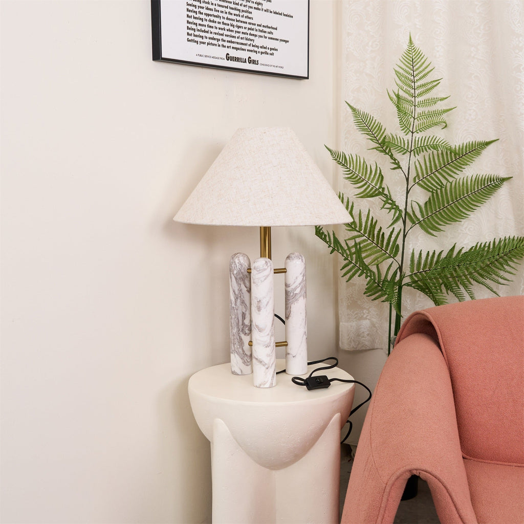 Closer crop of the Clérachic lamp's cord and switch by a wall socket, the coral armchair's arm just entering the frame.
