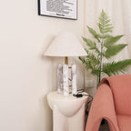 Closer crop of the Clérachic lamp's cord and switch by a wall socket, the coral armchair's arm just entering the frame.
