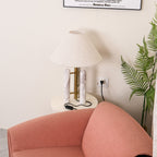 Tight crop of the room corner: mostly the coral armchair and a wall socket, with only the Clérachic lamp's shade edge in view.