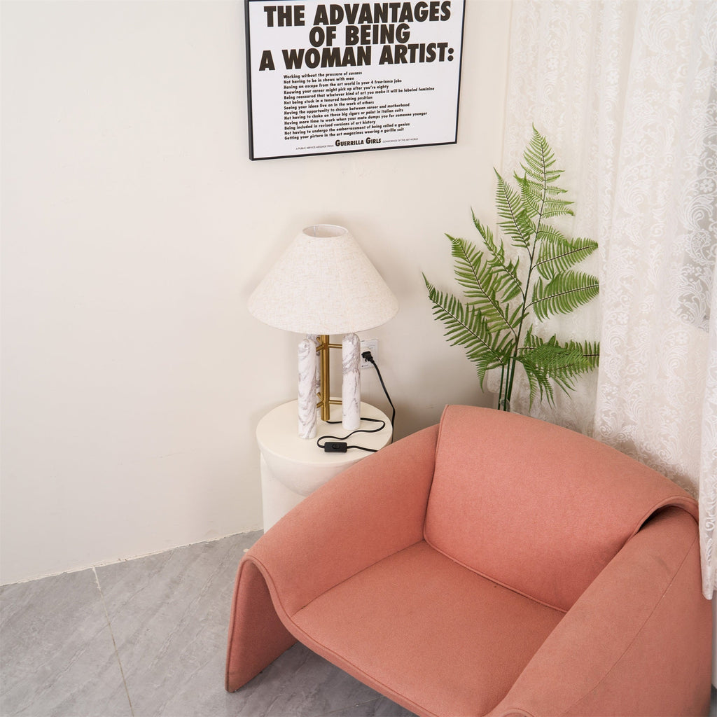 Clérachic table lamp lit in the room corner, a framed print on the wall above and the coral armchair filling the foreground.