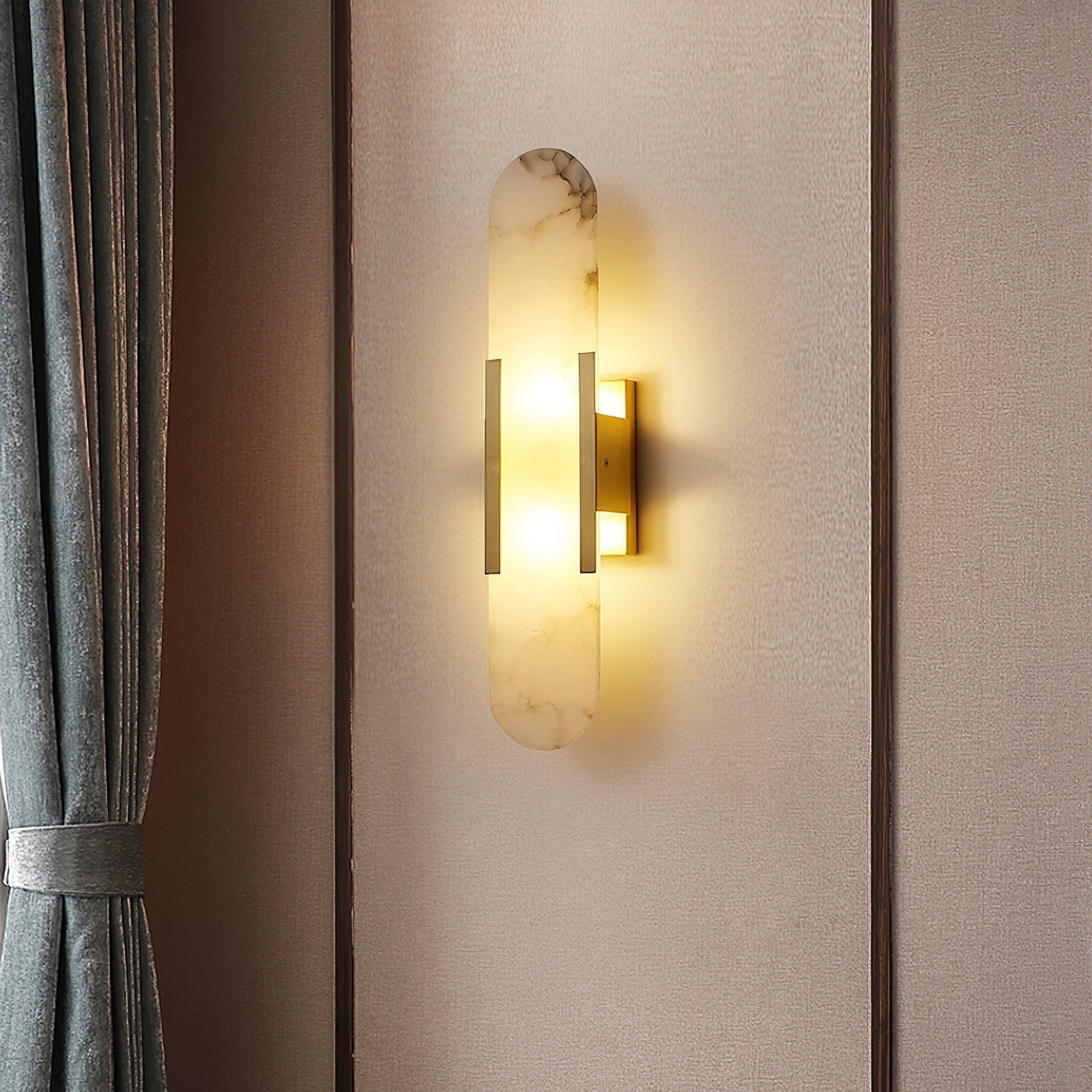 Clérachic veined alabaster Olraeia sconce lit on a fabric-panelled wall beside a tied-back grey curtain