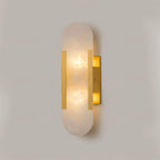 Clérachic brass Olraeia Alabaster Wall Sconce lit head-on, warm light pooling through the veined capsule panel