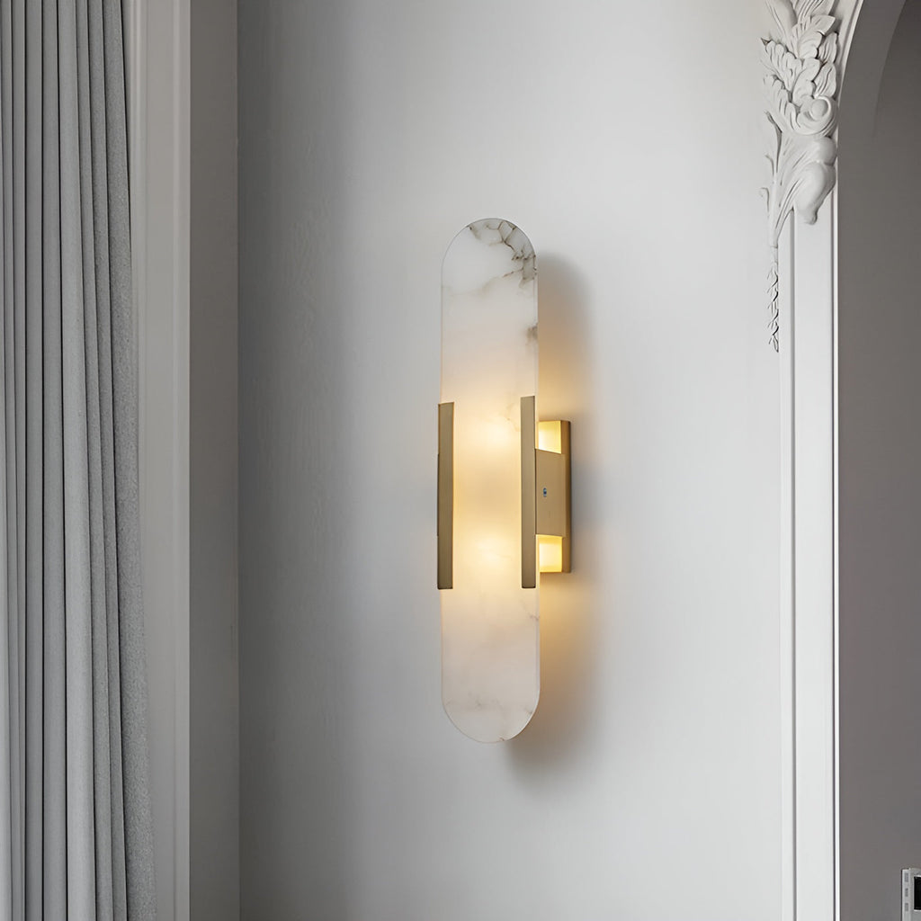 Clérachic brass Olraeia sconce lit in a hallway corner by a carved plaster arch and pleated grey curtain