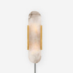 Brass Kristy alabaster sconce lit on white, heavy natural veining running through the stone