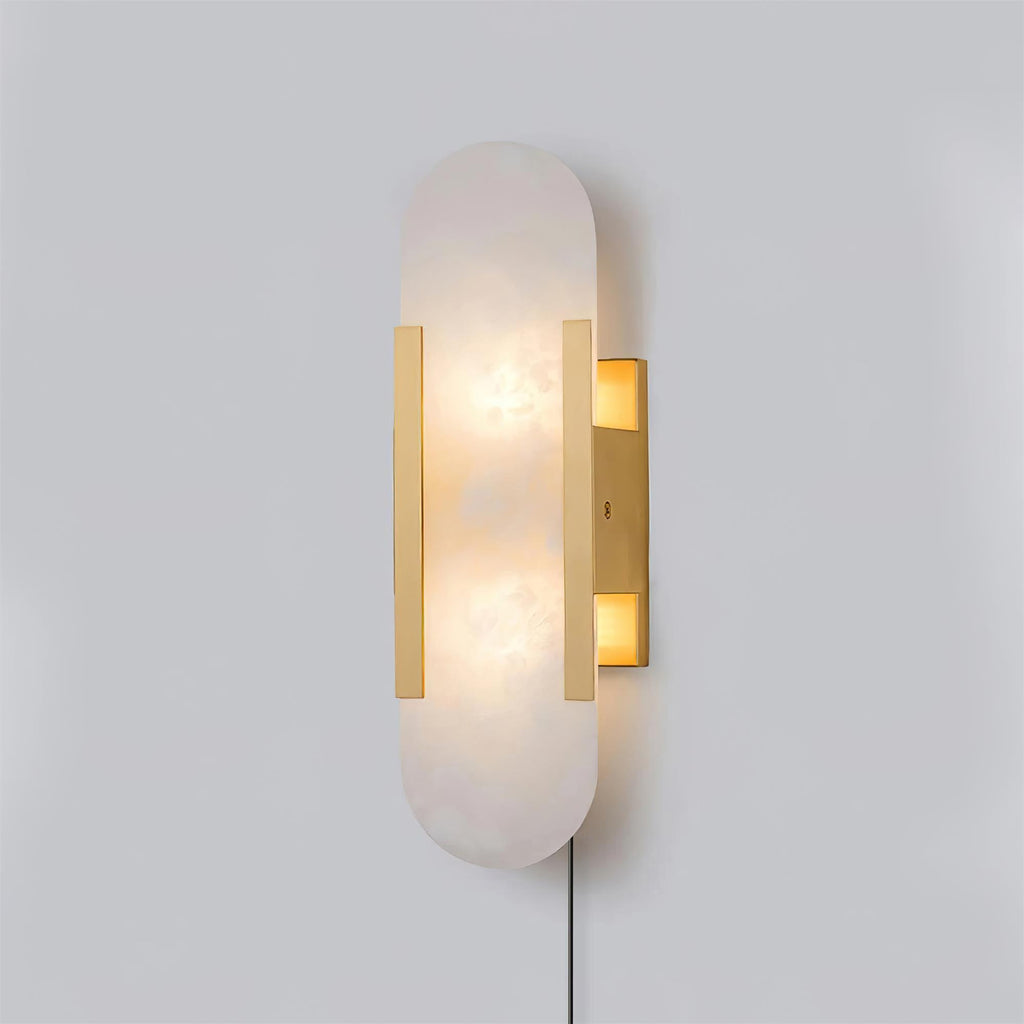 Brass-finish Kristy alabaster wall lamp lit at an angle, plug-in cord trailing from the backplate