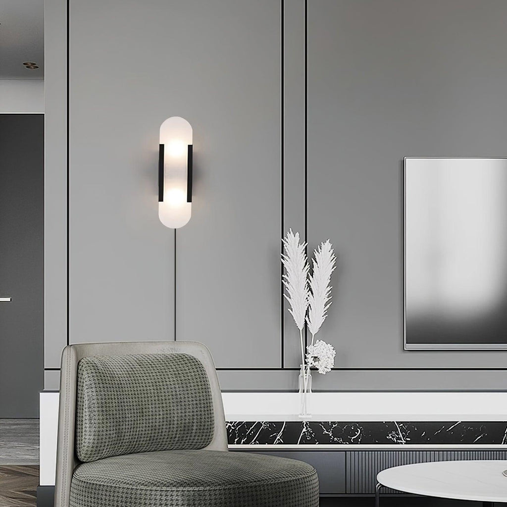 Black Kristy sconce lit on a grey panelled wall above a green houndstooth chair